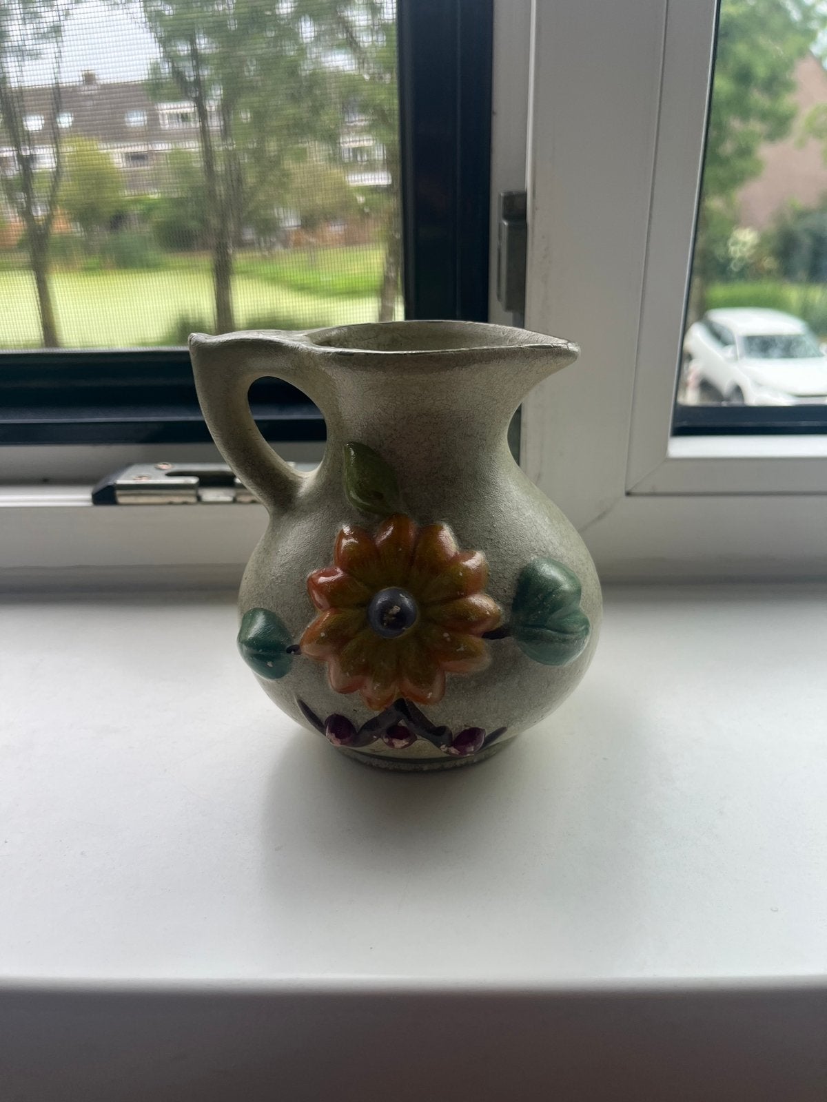 schenkkannetje met een reliëf bloemmotief in aardse tinten., Ophalen of Verzenden