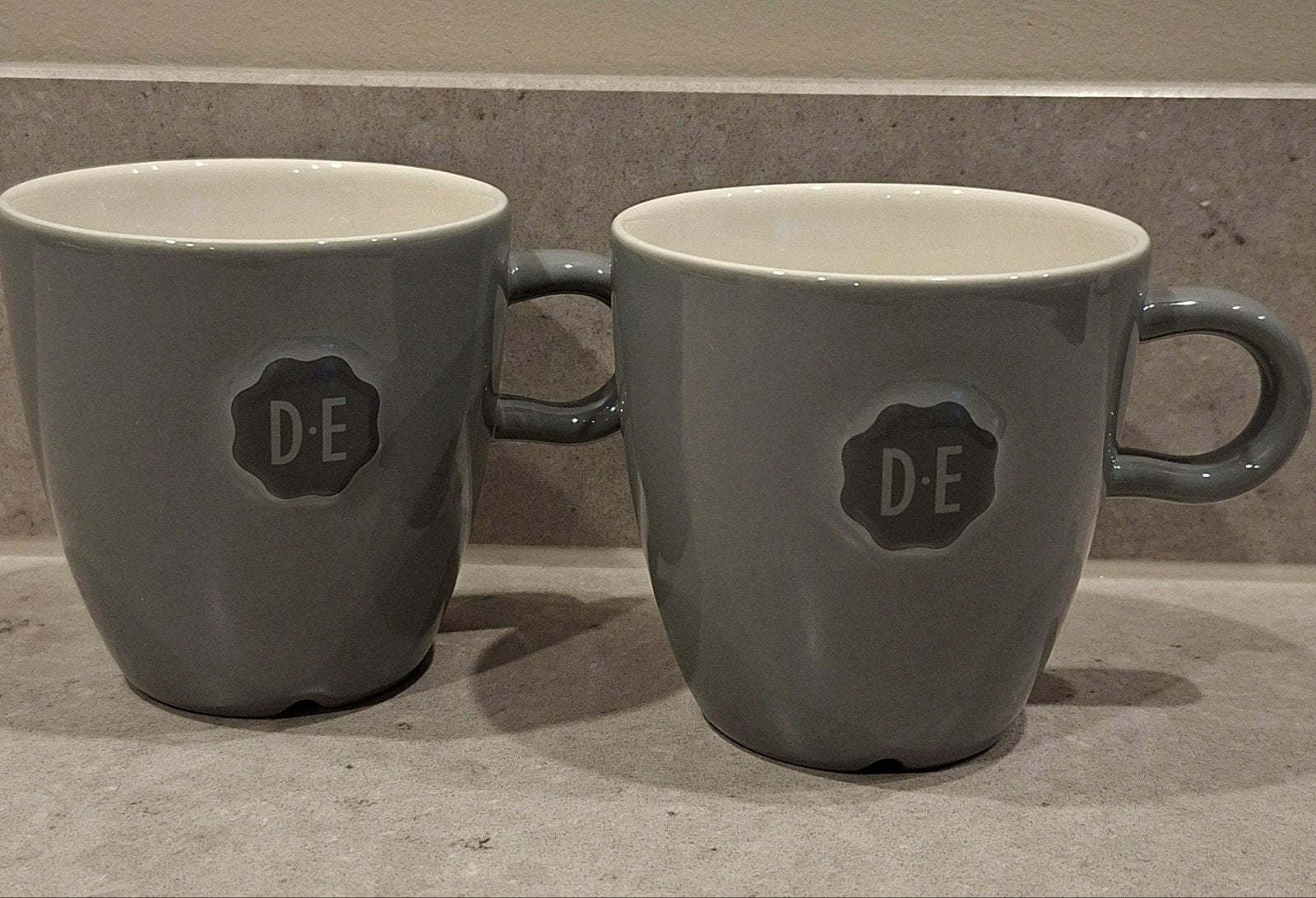 Set van 2 Douwe Egberts (D.E) Mokken –  Nikolai Carels, Huis en Inrichting, Overige merken, Keramiek, Nieuw, Ophalen of Verzenden