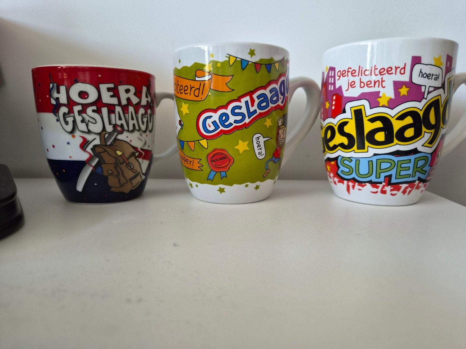 3 vrolijke 'Hoera Geslaagd' mokken, Ophalen of Verzenden, Steen/keramiek, Meerkleurig, Overige merken