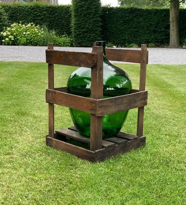 Smaragdgroene mondgeblazen glazen fles in houten krat, Ophalen