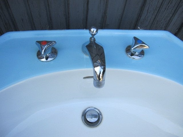 Blauwe vintage wastafel op zuil, handdoekstang en planchet