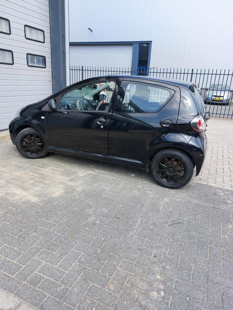 Toyota Aygo 1.0 12V Vvt-i 5DRS 2011 Zwart, Auto's, Voorwielaandrijving, Stof, 4 stoelen, Handgeschakeld