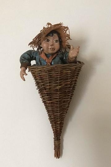 Wanddecoratie: rieten mandje met pop (jongen) beschikbaar voor biedingen