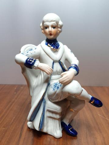 Vintage porselein beeldje met een mannenfiguur op een stoel. beschikbaar voor biedingen
