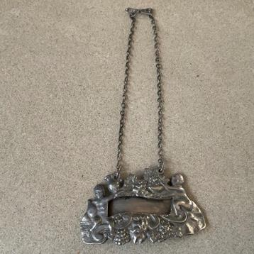 Rijk gedecoreerde karaf label van zilver met o.a. engeltjes  beschikbaar voor biedingen