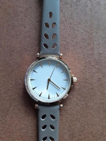 Dames horloge,  goudkleurige kast en taupe band. Nieuw  beschikbaar voor biedingen