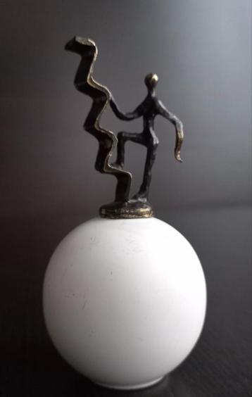 Beeldje figuur die een zigzaglijn beklimt op een witte bol  beschikbaar voor biedingen