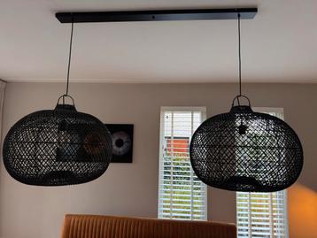 Zwarte rotan hanglamp met twee kappen aan een balk