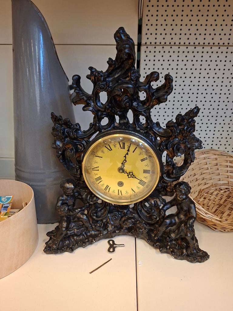 Antieke gietijzeren schoorsteenmantelklok met cherubijnen, Ophalen of Verzenden