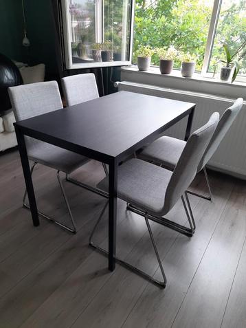 zwarte tafel met 4 grijze stoelen