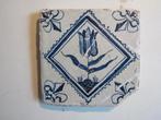 een 17e eeuwse tegel met een tulp in quadraat., Antiek en Kunst, Antiek | Wandborden en Tegels, Ophalen of Verzenden