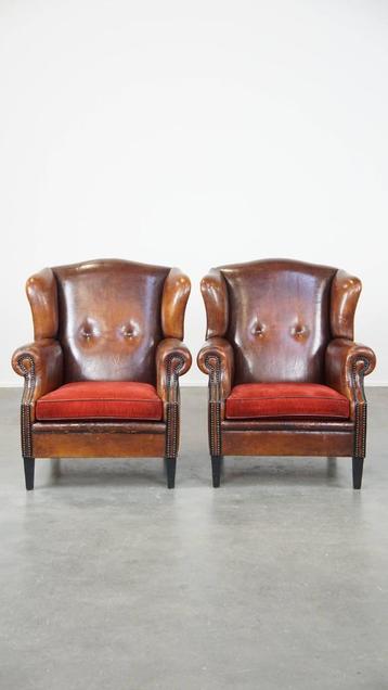 2 x Vintage schapenleren oorfauteuil met een rood zitkussen beschikbaar voor biedingen