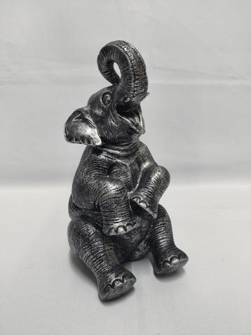 Zilver gekleurde zittende olifant met slurf omhoog. beschikbaar voor biedingen
