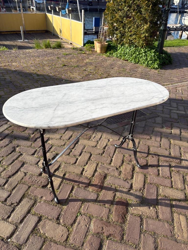 Ovale marmeren terrastafel met gietijzer onderstel, Ophalen, Gebruikt, 100 tot 150 cm, 50 tot 100 cm