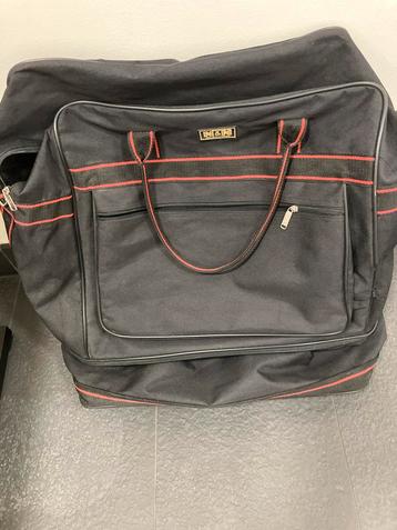 Grote zwarte reistas met rode accenten beschikbaar voor biedingen