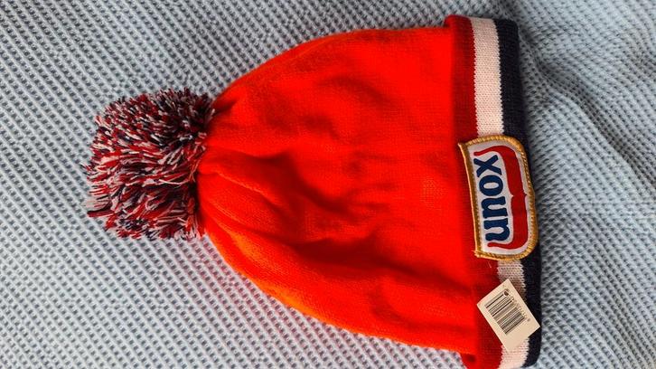 Nieuwe oranje Unox muts met een leuke pompon., Kinderen en Baby's, Kinderkleding | Mutsen, Sjaals en Handschoenen, Nieuw, Muts