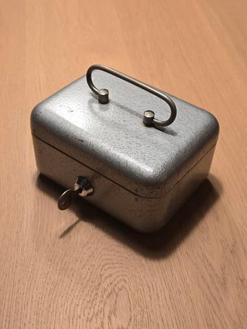 Antiek klein grijs gemêleerd kluisje met sleutel en rode bin beschikbaar voor biedingen