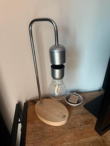Design tafellamp in zwevend model met houten voet beschikbaar voor biedingen