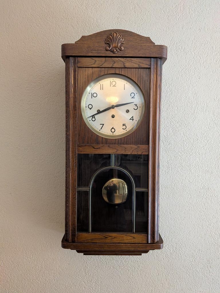 Antieke wandklok uitgevoerd in een donker eikenhouten kast, Ophalen