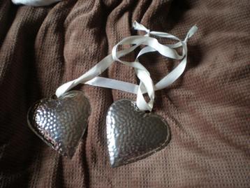 2 zilverkleurige aluminium harten aan wit lint.