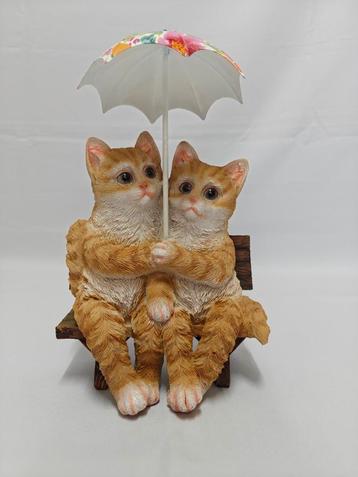 Poezen op bankje onder paraplu. Rode kater poes Kater. beschikbaar voor biedingen