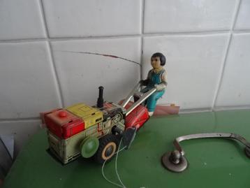 Antiek oud blikken speelgoed man op grasmaaier beschikbaar voor biedingen