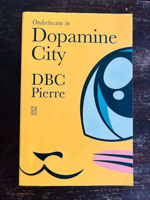 Dbc Pierre - Ondertussen in Dopamine City, Boeken, Literatuur, Zo goed als nieuw, Nederland, Ophalen of Verzenden