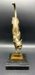 Bronzen kat die van de trap afloopt.