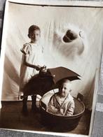 Oude foto van twee kinderen in bad met paraplu.