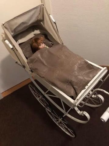 Antieke poppenkinderwagen met pop beschikbaar voor biedingen