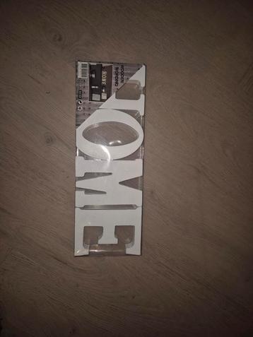 Houten tekst HOME beschikbaar voor biedingen