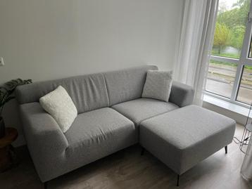 Grijze driezitsbank met hocker
