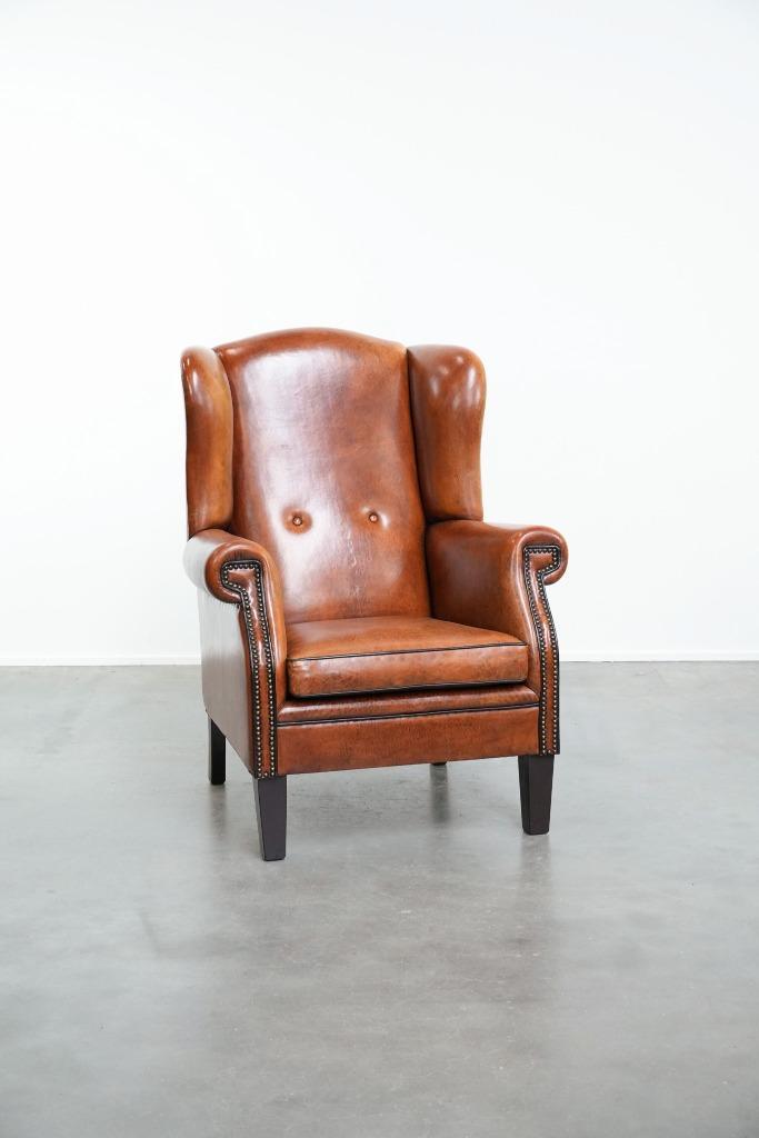 Schapenleren oorfauteuil met zwarte biezen en siernagels, Huis en Inrichting, Fauteuils, Zo goed als nieuw, Leer, 75 tot 100 cm