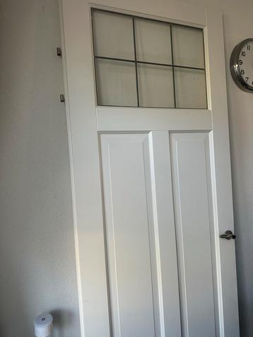 Witte deur met raam en metalen klink beschikbaar voor biedingen