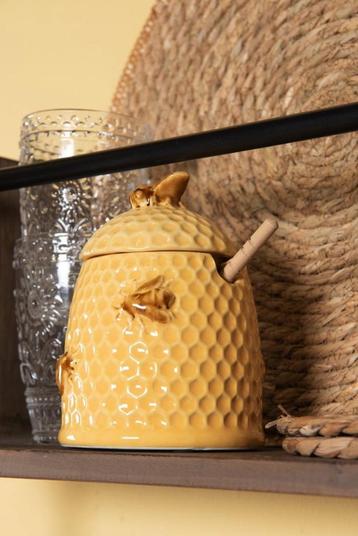 Gele landelijke honingpot met een lepel en bijen beschikbaar voor biedingen