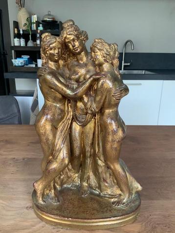 Goudkleurig beeld van drie schaarsgeklede dames beschikbaar voor biedingen