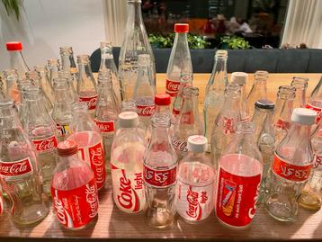 Gratis Verzameling Coca Cola glazen flessen +/- 52 stuks beschikbaar voor biedingen