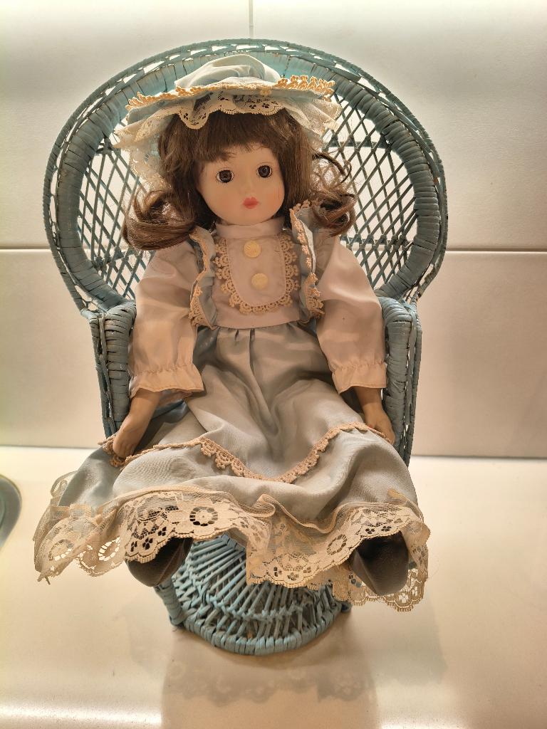 porseleinen pop in rotan stoel, Verzamelen, Poppen, Ophalen of Verzenden, Zo goed als nieuw, Pop