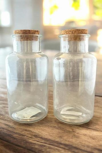 Een paar doorzichtige glazen flessen met kurken doppen. beschikbaar voor biedingen