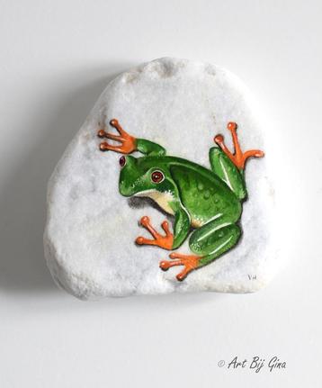 Groene boomkikker geschilderd op een mooie riviersteen beschikbaar voor biedingen