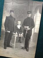 Foto uit begin 1900 van 2 soldaten met sabel en kind.