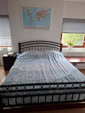 Tweepersoonsbed met houten frame en metalen details beschikbaar voor biedingen