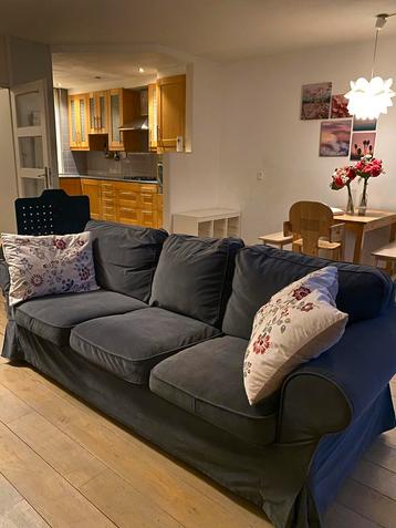 Donkergrijze bank met kussens beschikbaar voor biedingen