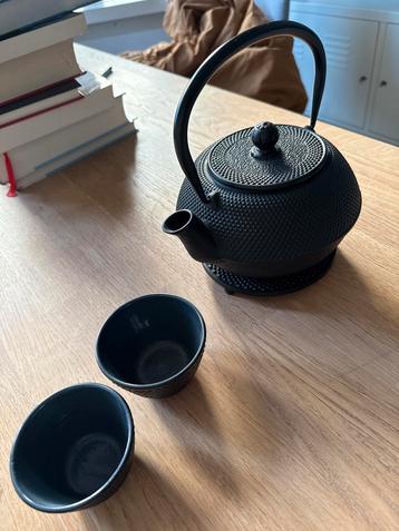 Zwarte gietijzeren theepot met kopjes beschikbaar voor biedingen