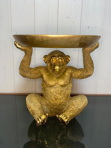 Zittende aap met schaal goud beschikbaar voor biedingen