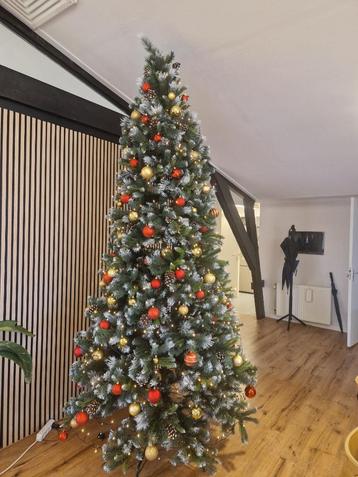 Besneeuwde kerstboom met dennenappels, lichtjes & ballen beschikbaar voor biedingen