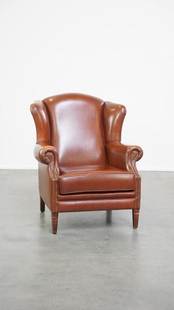Luxe oorfauteuil gemaakt van cognac kleurig rundleer beschikbaar voor biedingen
