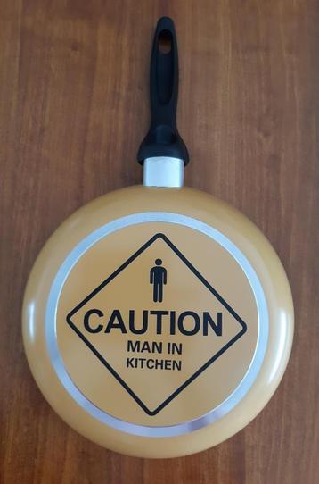 Koekenpan met tekst Caution Man in Kitchen beschikbaar voor biedingen