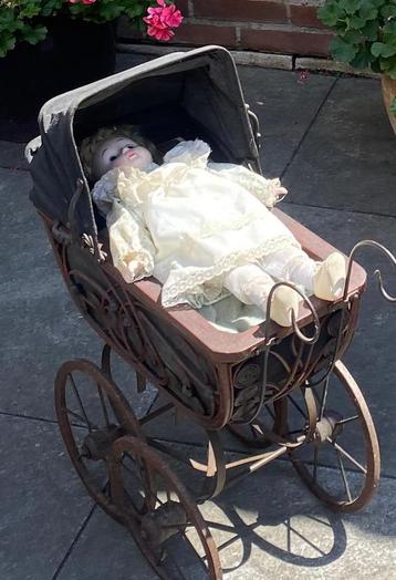 Antieke kinderwagen met porseleinen pop beschikbaar voor biedingen