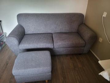 Te koop, grijze 2,5 zits bank met poef beschikbaar voor biedingen